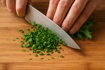 Ahşap tahtada ince doğranan taze otlar ve keskin şef bıçağı