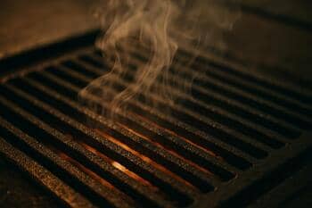 Sokak ızgarasında yükselen hafif duman ve ızgara izleri