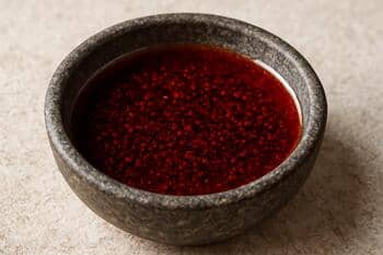 Sumakla renklendirilmiş yağlı dip sos; küçük taş kâse