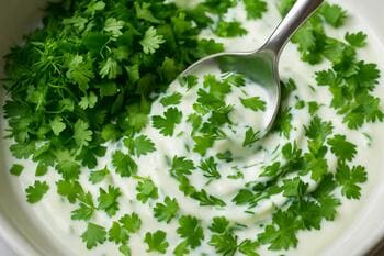 İnce doğranmış dereotu ve kişnişin yoğurda katlanışı